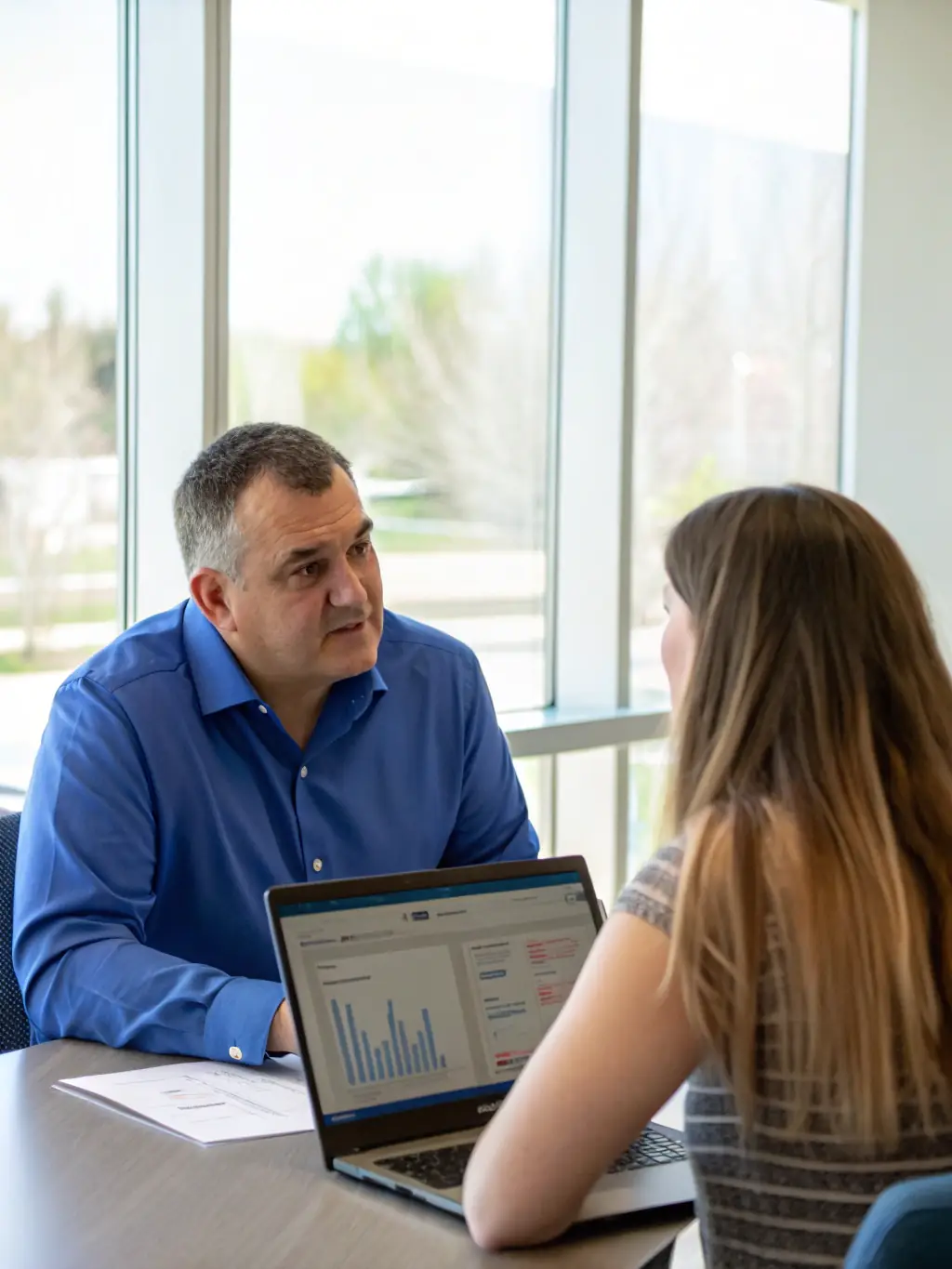 A consultant reviewing a business strategy document with a client, highlighting key areas for improvement and profitability enhancement.